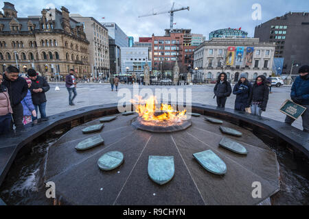 OTTAWA, Kanada - 10. NOVEMBER 2018: Centennial Flam, vor dem Kanadischen Parlament, mit Touristen Erwärmung. Der Brunnen und sein Feuer zu gedenken. Stockfoto