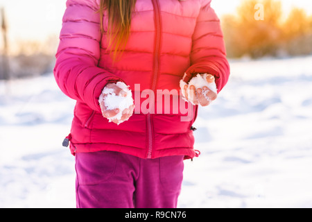 Ein kleines Mädchen hält Schnee in ihre Hände an einem sonnigen Wintertag. Soft Focus. Stockfoto