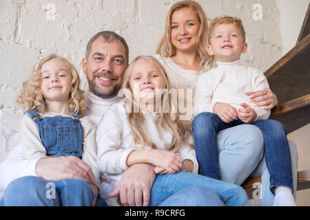 Happy Family auf der Treppe, zu Hause zu sitzen. Stockfoto