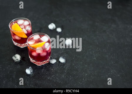 Negroni Cocktail mit Orangen und Eis. Hausgemachte klassische Negroni Cocktail und Zutaten auf schwarzem Hintergrund, kopieren. Stockfoto