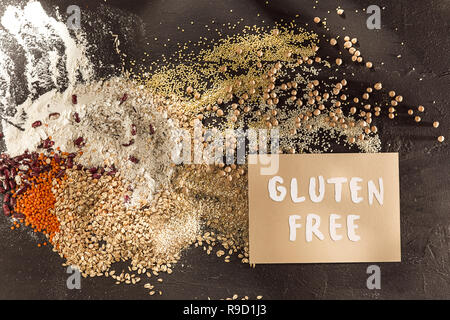 Glutenfreies Mehl und Getreide, Hirse, Quinoa, Maisbrot, braun Buchweizen, Reis, Brot und Pasta mit Text Gluten in englischer Sprache kostenlos mit Löffel auf Holz- Hintergrund, Ansicht von oben Stockfoto