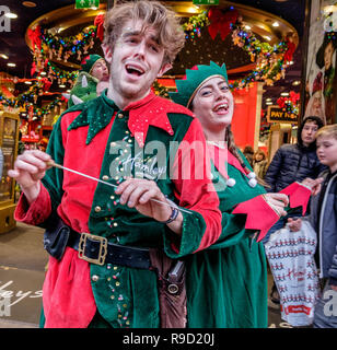 Elf Mike Rogers singt mit einer weiblichen elf vor hamleys Toy Store in der Regent Street. Weihnachten, 2018. Stockfoto