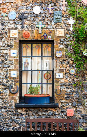 Fenster der kleinen Feuerstein und Ziegel Terrasse Haus auf der Vorderseite mit verschiedenen christlichen religiösen Symbole und Abzeichen geschmückt. Church Square, Broadstairs. Stockfoto