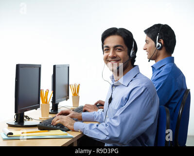 Mann IN CALL CENTER AUF KOPFHÖRER Stockfoto