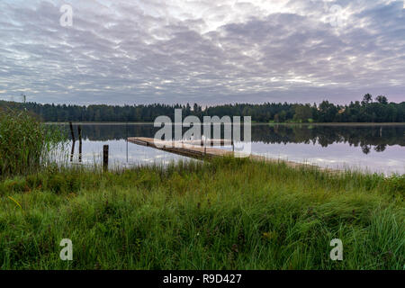 Picknick am See mit holzbrett Promenade in der Sonnenuntergang mit ruhigem Wasser Stockfoto