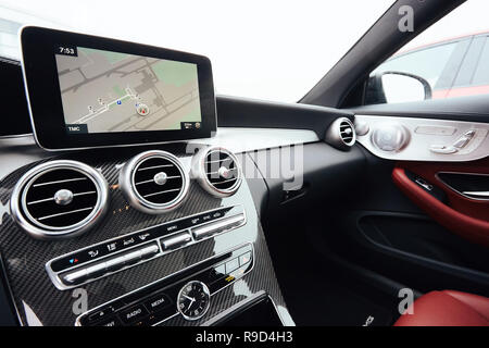 Blick vom in einem Auto auf einen Teil des Dashboards mit einer Navigationseinheit und unscharfen Straße vor ein Auto Stockfoto