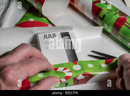Box holding JUUL Nikotin Dispenser und Schoten auf Weihnachten Papier Stockfoto