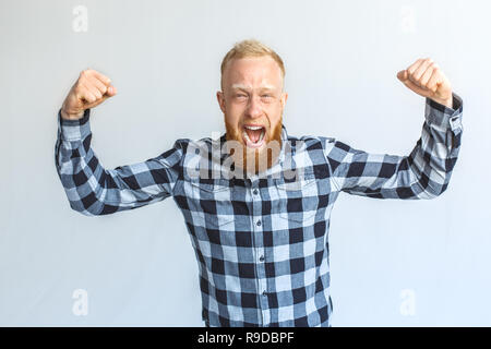 Rote Haare reifer Mann stehend auf graue Wand halten Hände in den Fäusten, schrie aufgeregt Erfolg Leistung isoliert Stockfoto