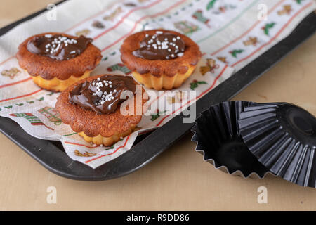 Leckere Cupcakes mit Schokolade verziert. Dessert auf einen Holztisch in der Küche. Hellen Hintergrund. Stockfoto