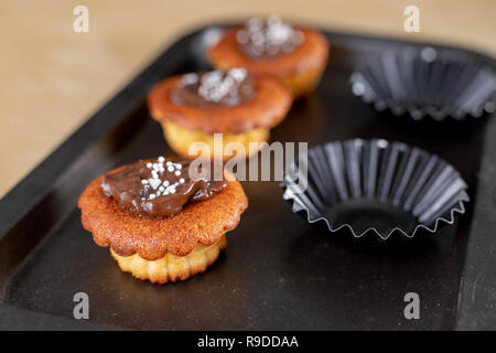 Leckere Cupcakes mit Schokolade verziert. Dessert auf einen Holztisch in der Küche. Hellen Hintergrund. Stockfoto