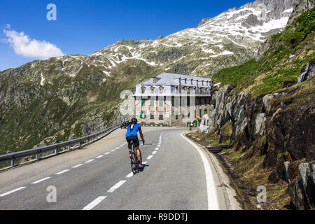 Ein Radfahrer absteigend auf dem Weg zum Furka Pass (2.429 m), eine der spektakulärsten Straßen in den Schweizer Alpen. Furka Pass, Wallis, Schweiz Stockfoto