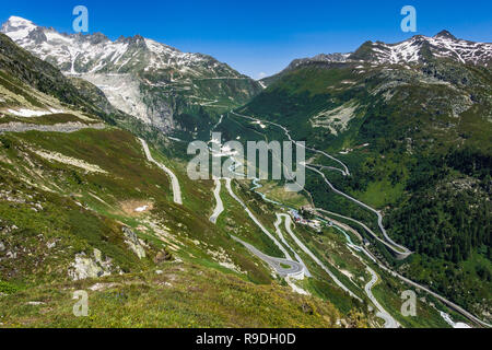 Alpine Landschaft des Oberen Wallis: Im Vordergrund der Weg zum Grimselpass, auf dem Hintergrund der Straße zum Furkapass, unten im Tal. Stockfoto