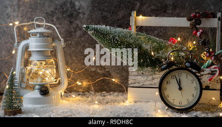 Foto von Laternen, Uhr, Box mit Weihnachtsbaum, brennen Girlande auf schwarz Tabelle Stockfoto