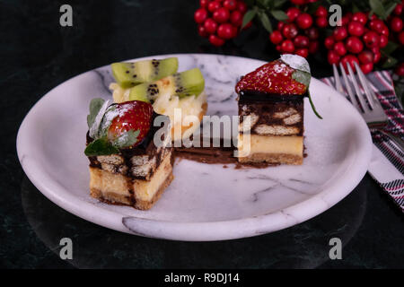 Winzige Cupcake mit Kiwi, Sahne und Schokolade Kuchen auf schwarzem Marmor tisch Stockfoto