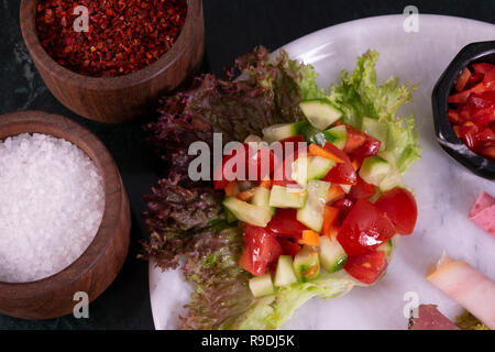 Fleisch Platte mit dünn geschnittene Salami und Schinken mit Salat auf dem Marmor Hintergrund Stockfoto