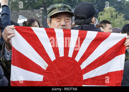 Tokio, Japan. 23 Dez, 2018. Ein Mann zeigt einen Krieg Flagge der Kaiserlichen Japanischen Armee außerhalb des Imperial Palace. Menschen versammeln sich von Kaiser Akihito Geburtstag im Imperial Palace zu feiern, seine letzte in seiner 30-jährigen Regierungszeit. Akihito wird im nächsten April 30, Abzudanken, der von seinem ältesten Sohn, Kronprinz Naruhito, am 1. Mai. Credit: Rodrigo Reyes Marin/ZUMA Draht/Alamy leben Nachrichten Stockfoto