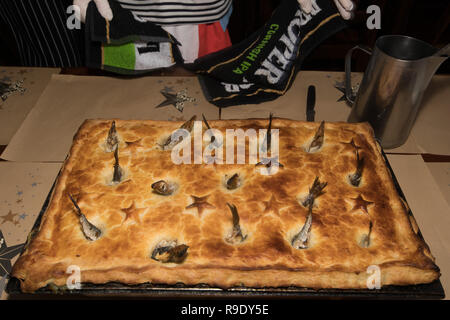 Fowey, Cornwall, UK. 23 Dez, 2018. Lokale 'Guns'Madron, als Tom Bawcock bringen traditionelle Stargazy pie in The Ship Inn in Fowey. Der fisch Pie mit Sardine Köpfe und Schwänze, stößt, ist in der Kneipe auf Tom Bawcocks Eve Die Geschichte geht, dass Tom, ein aus dem 16. Jahrhundert Fischer, trotzte Stürmen und verfing sich genug Fisch im ganzen Dorf zu füttern. Foto: Simon Maycock/Alamy leben Nachrichten Stockfoto