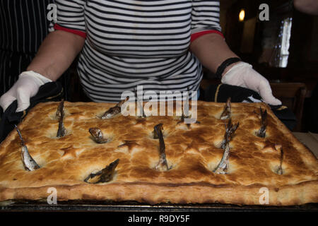 Fowey, Cornwall, UK. 23 Dez, 2018. Mitarbeiter aus dem Ship Inn in der traditionellen Stargazy pie in The Ship Inn in Fowey. Der fisch Pie mit Sardine Köpfe und Schwänze, stößt, ist in der Kneipe auf Tom Bawcocks Eve Die Geschichte geht, dass Tom, ein aus dem 16. Jahrhundert Fischer, trotzte Stürmen und verfing sich genug Fisch im ganzen Dorf zu füttern. Foto: Simon Maycock/Alamy leben Nachrichten Stockfoto