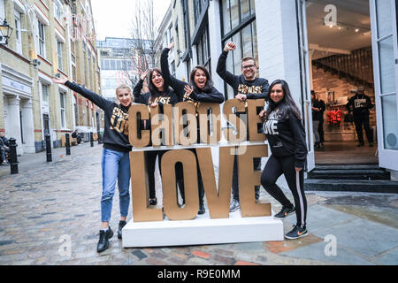 London, Großbritannien. 23. Dezember 2018. Die Mitarbeiter an der Pop-up Stores pose mit der Wählen Sie 'Liebe' Zeichen außerhalb des Store. sind alles Freiwillige, die 'Liebe' Weihnachten Einblendmenü "Geschäft nur an Londons Carnaby Street in Soho, die von der Nächstenliebe helfen Flüchtlingen organisiert, das tosende Weihnachten Handel mit Geschenken und Elemente zugunsten der Flüchtlinge in der Hilfe bedürfen. Credit: Imageplotter Nachrichten und Sport/Alamy leben Nachrichten Stockfoto