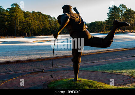 Pinehurst, North Carolina, USA. 23 Dez, 2018. Dezember 23, 2018 - Pinehurst, N.C., USA - die Statue von Payne Stewart ist gegen die aufgehende Sonne mit Blick auf den 18. Grün an der berühmten Pinehurst Nr. 2 Kurs. Die lebensgroße Bronzeskulptur von Zenos Furdakis, erinnert an Stewart's Pose nach dem Gewinn der US Open 1999 bei Pinehurst. Credit: Timothy L. Hale/ZUMA Draht/Alamy leben Nachrichten Stockfoto