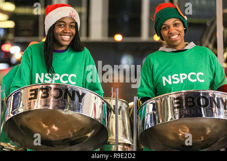 London, Großbritannien. 23. Dez 2018. Eine stahl Band spielt für Nächstenliebe NSPCC. Käufer mit Last-Minute-Einkäufe durch die Verkäufe im West End von London am Sonntag Ansturm vor Weihnachten, die in der bunten Dekorationen und faszinierenden Licht zeigt in der Hauptstadt. Credit: Imageplotter Nachrichten und Sport/Alamy leben Nachrichten Stockfoto