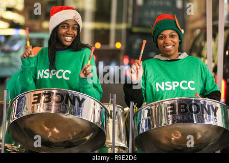 London, Großbritannien. 23. Dez 2018. Eine stahl Band spielt für Nächstenliebe NSPCC. Käufer mit Last-Minute-Einkäufe durch die Verkäufe im West End von London am Sonntag Ansturm vor Weihnachten, die in der bunten Dekorationen und faszinierenden Licht zeigt in der Hauptstadt. Credit: Imageplotter Nachrichten und Sport/Alamy leben Nachrichten Stockfoto