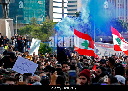 Beirut, Libanon. 23 Dez, 2018. Die Demonstranten halten Libanesische Fahnen und Banner bei einer Demonstration in Beirut, Libanon, 23 Dezember, 2018. Tausende von Demonstranten auf die Straße gingen, in Beirut am Sonntag gegen die Verschlechterung der wirtschaftlichen Rahmenbedingungen zu protestieren. Der Libanon hat gekämpft, um eine Regierung zu bilden, da Saad Hariri als Premierminister im Mai bestimmt war, mit tiefen Unterschiede zwischen den Parteien über ihre Darstellung in der neuen Regierung. Credit: Bilal Jawich/Xinhua/Alamy leben Nachrichten Stockfoto