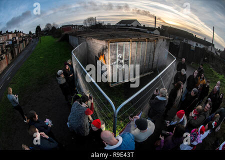 Die Menschen sammeln sich um Zäune errichtet die neuesten Kunstwerke von Banksy auf eine Garage an der Wand in der Taibach Bereich von Port Talbot in South Wales zu schützen. Stockfoto