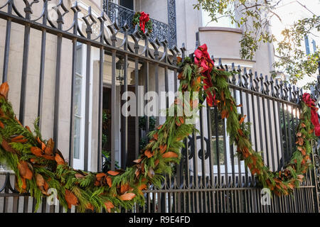 Traditionelle magnolia roping schmückt das eiserne Tor Eingang zu einem historischen Haus für die Weihnachtsfeiertage auf Sitzung Straße in Charleston, South Carolina. Stockfoto