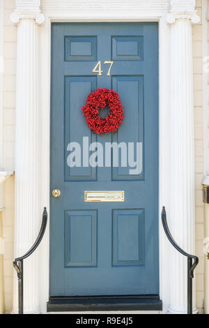 Ein dezenter traditionellen roten Popcorn berry Weihnachten Kranz schmückt die hölzerne Tür auf einem historischen Haus für die Feiertage auf Tradd Straße in Charleston, South Carolina. Stockfoto