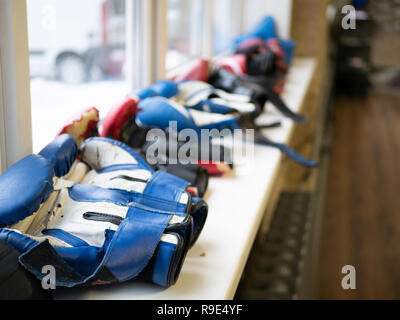 Reihe von Sportswear Leder Boxhandschuhe auf einer Fensterbank in Fitness Gym. selektive Fokus auf den ersten paar Handschuhe, andere Unscharf im Hintergrund Stockfoto
