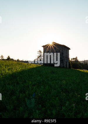 Ruhige, einsame Hütte aus Stein auf einer Wiese bei Sonnenaufgang Stockfoto