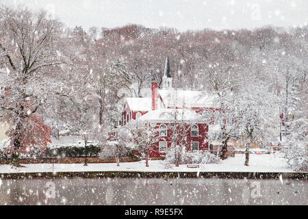 Schönen ländlichen Winterlandschaft mit Kirche, Bäume, Teich mit fallendem Schnee Stockfoto