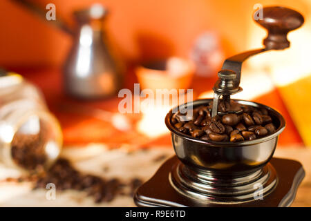 Körner aus gerösteten Arabica Kaffee mit Kaffeemühle, Türken, einem Glas auf einem Bambus matte und hölzernen Tisch in natürlichem Licht, die Sonne. Stockfoto