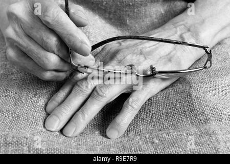 Gläser in die Hände einer alten Frau. Teil des Körpers. Stockfoto