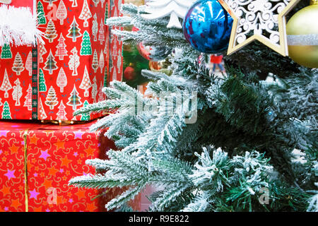 Einige Zweige der geschmückten Weihnachtsbaum und einem grossen roten Kisten mit Weihnachtsgeschenke Stockfoto