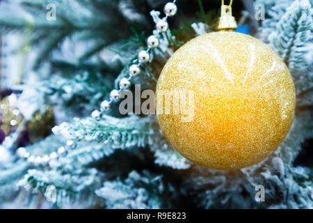 Einige Zweige der eingerichteten snowy christmas tree mit wunderschönen Golden Christmas Ball closeup Stockfoto