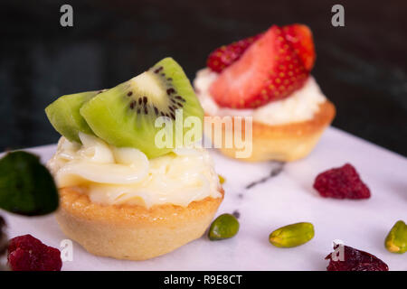 Kiwi und Erdbeeren Dessert Obst Törtchen Gebäck mit gepeitschter Creme, Dessert-Kuchen Stockfoto