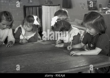 1948, nach dem Zweiten Weltkrieg Großbritannien, Bild zeigt eine kleine Gruppe von jungen Mädchen, Krieg Flüchtlinge aus osteuropäischen, sitzen zusammen mit Papier und Bleistift an einem Holztisch in Ihrem Wohnraum. Stockfoto