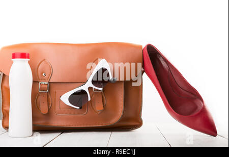 Travel Concept - Frauen mit Leder Tasche, Schuhe, Sonnenbrille und eine Flasche Wasser isoliert auf weiß gesetzt Stockfoto