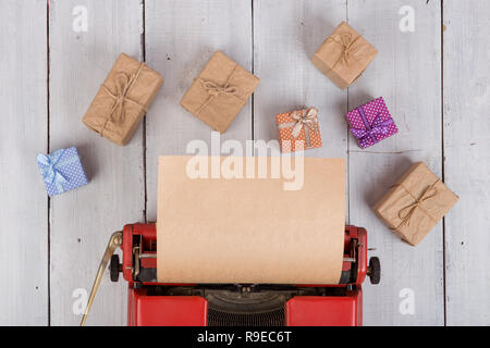 Urlaub Konzept - rot Schreibmaschine mit leeren Handwerk Papier, Geschenkboxen auf weißem Holz- Hintergrund Stockfoto