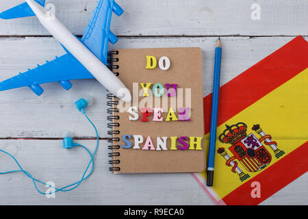 Konzept für das Erlernen der spanischen Sprache - wooden Briefe mit Text "o du Spanisch sprechen", Flagge Spanien, Modellflugzeug, Kopfhörer, pe Stockfoto