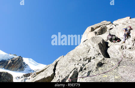 Bergführer suchen, um sich auf einem felsigen Aufstieg in den französischen Alpen mit Seil Teams vor ihm Stockfoto