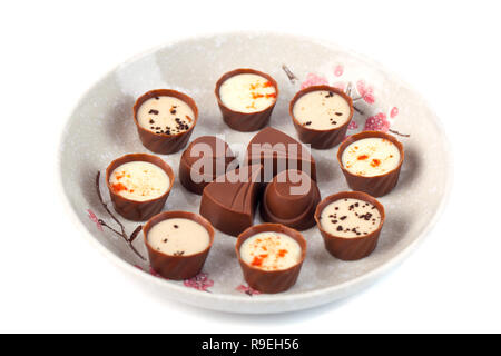 Verschiedene Schokoladen auf einer Platte auf einem weißen Hintergrund. Stockfoto