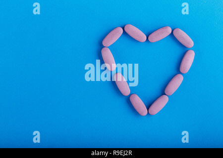 Rosa Pillen in der Form eines Herzens auf einem Tisch verstreut. Heilung für Herz Schmerz. Platz für Text Stockfoto