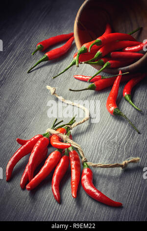 Nahaufnahme auf red hot chili peppers mit einem String auf dunklem Hintergrund gebunden. Essen Hintergrund. Stockfoto