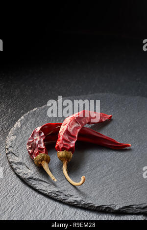 Nahaufnahme auf zwei trockene rote Chilischoten auf schiefer Hintergrund. Essen Hintergrund. Stockfoto