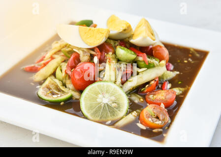 Pikanter Gurkensalat Ei/Thai Gurke in Scheiben schneiden mix Zutaten kochen Kräuter Tomate garnieren Kalk und gekochtes Ei auf weiße Platte - traditionelle Thai Stil Stockfoto
