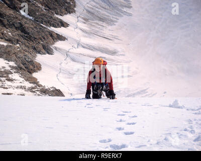 Weibliche Kletterer auf einem steilen Nordwand erreicht den Gipfel eines hohen Berges Stockfoto