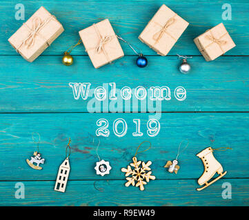 Text "Willkommen 2019", Weihnachten oder Neujahr Geschenke und Weihnachten Spielzeug auf Blau Holz- Hintergrund Stockfoto